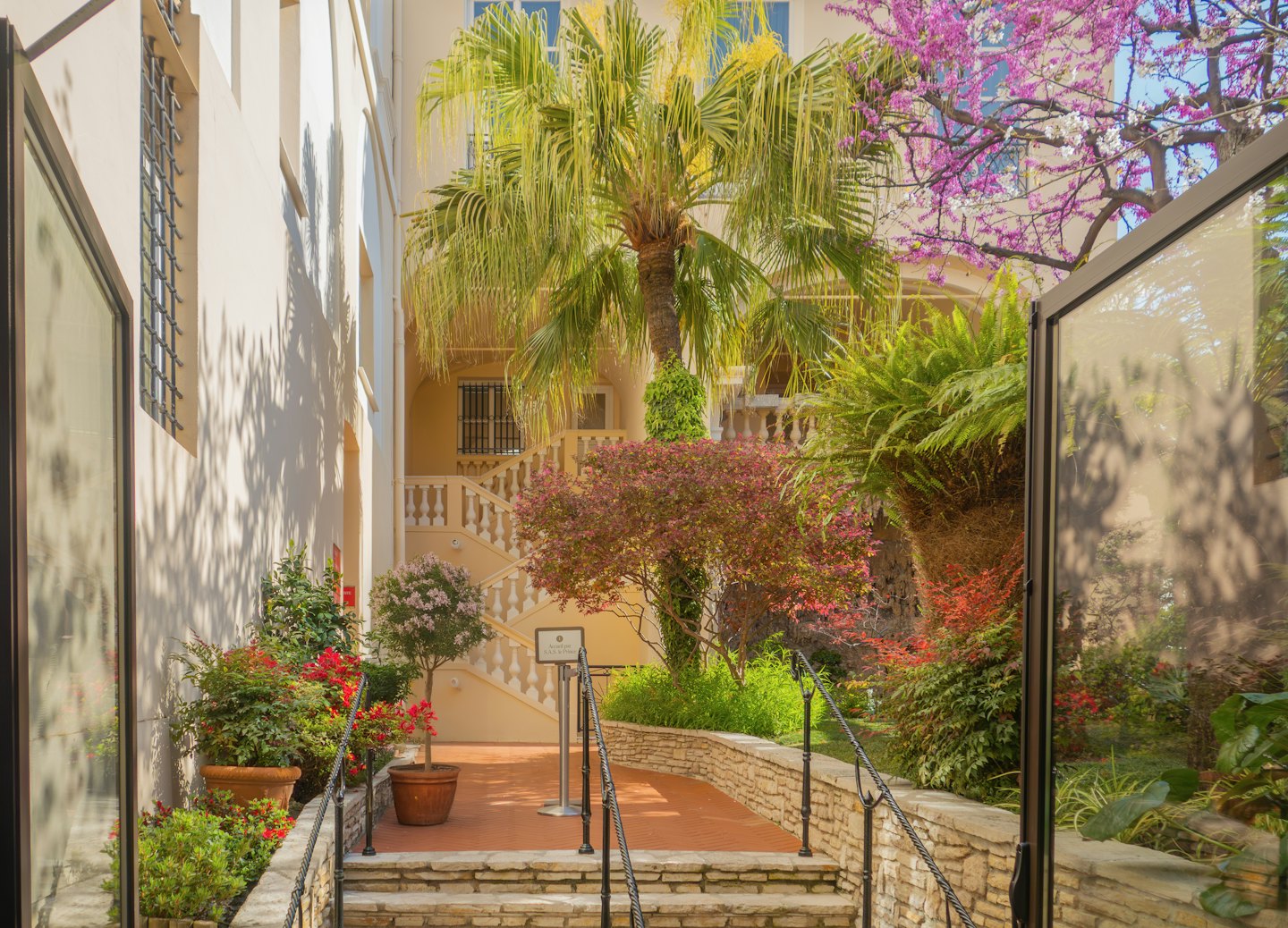 Terracotta path winding through a lush Mediterranean courtyard garden.
