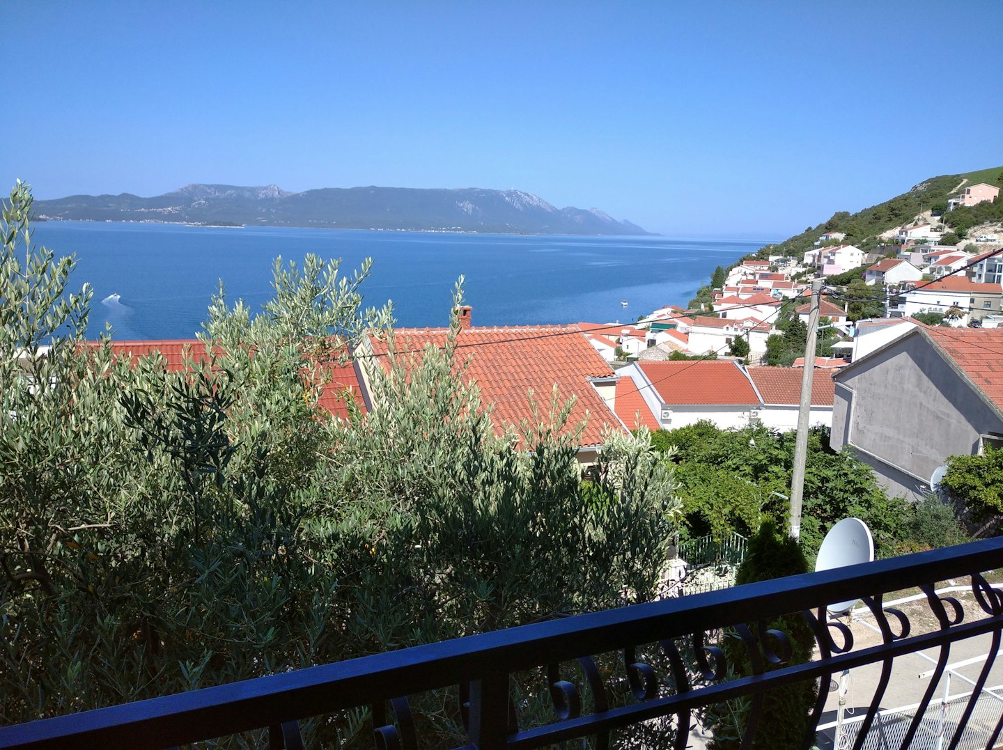 Mediterranean village houses overlook a coastal bay with a boat.